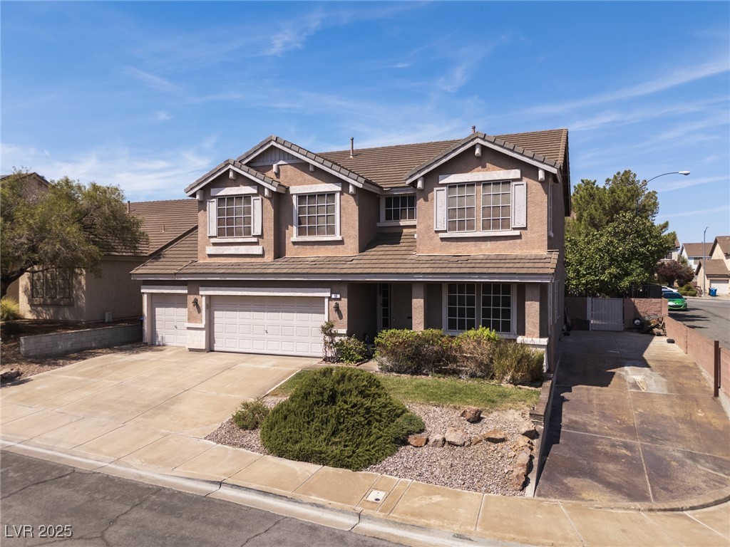 Traditional-style home featuring concrete driveway, a garage, a tile roof, and stucco siding