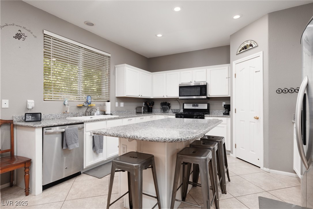 99 Milicity Road Henderson, NV 89012 - Photo 11 of 51 Kitchen with a breakfast bar area, stainless steel appliances, light stone countertops, light tile patterned floors, and recessed lighting