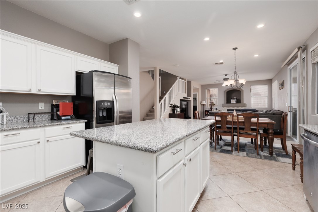 99 Milicity Road Henderson, NV 89012 - Photo 14 of 51 Kitchen featuring light stone counters, white cabinetry, recessed lighting, light tile patterned flooring, and a kitchen island