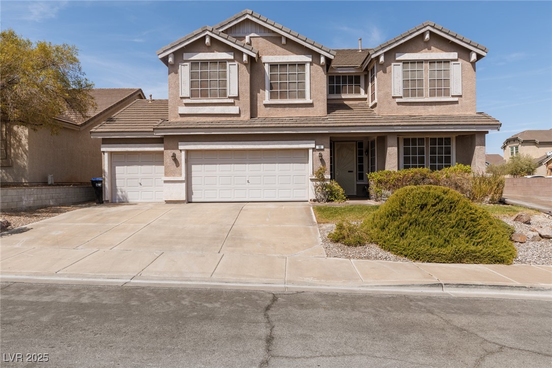 View of front facade with stucco siding, an attached garage, driveway, and a tile roof