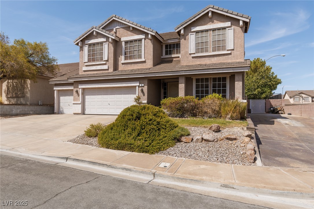 Traditional home with an attached garage, stucco siding, driveway, and a tile roof