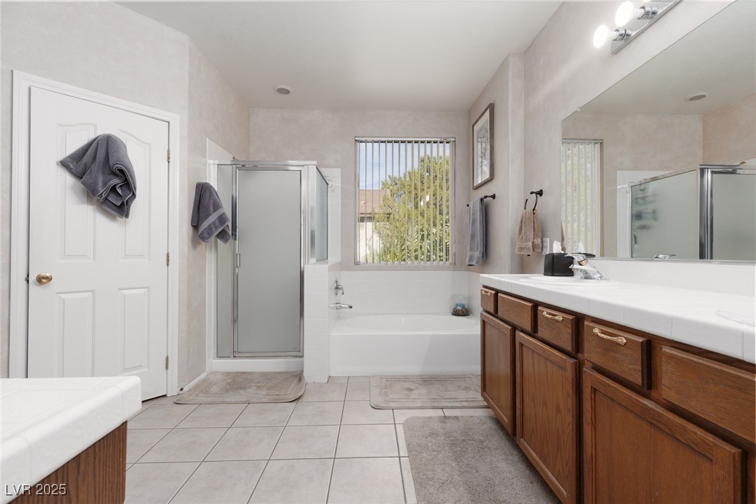 99 Milicity Road Henderson, NV 89012 - Photo 32 of 51 Bathroom with double vanity, a garden tub, light tile patterned flooring, and a shower stall