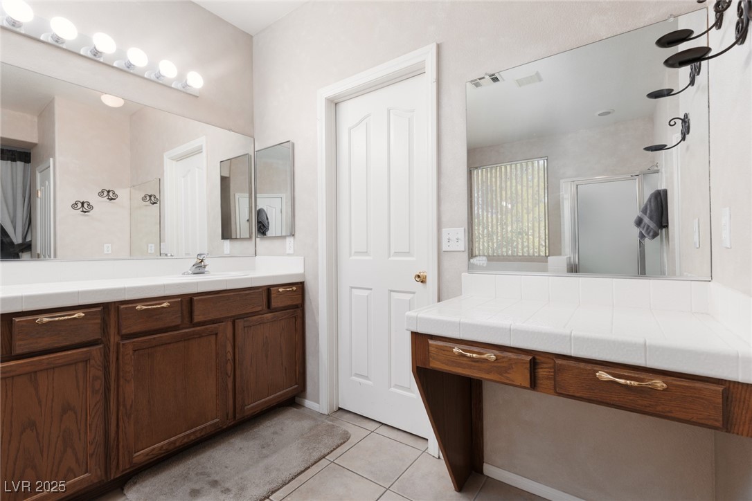 99 Milicity Road Henderson, NV 89012 - Photo 33 of 51 Bathroom featuring light tile patterned floors, a shower stall, and vanity