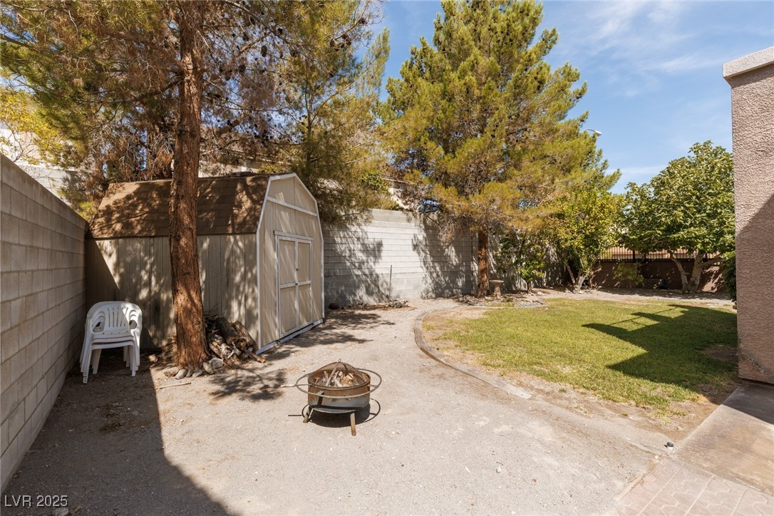 99 Milicity Road Henderson, NV 89012 - Photo 36 of 51 Fenced backyard with an outdoor fire pit and a storage shed
