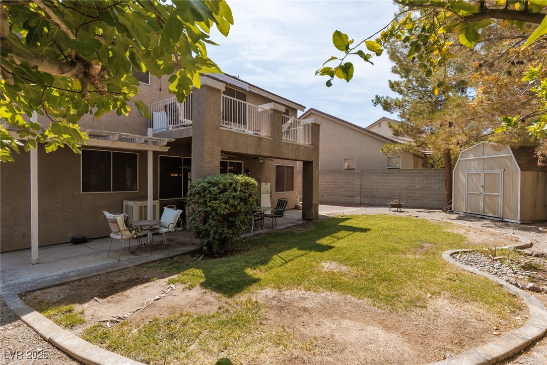 99 Milicity Road Henderson, NV 89012 - Photo 38 of 51 Rear view of house with a balcony, a storage shed, stucco siding, and a patio
