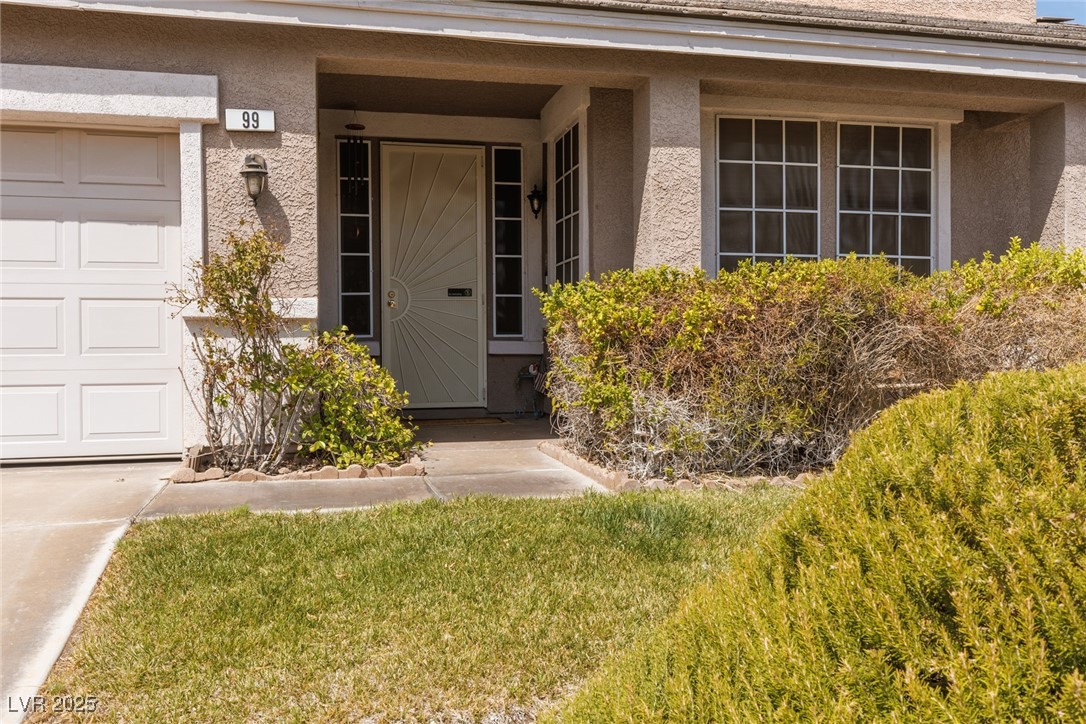 View of exterior entry featuring stucco siding, a garage, and covered porch