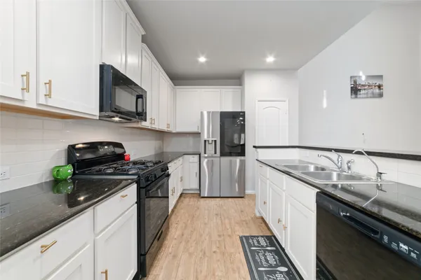 a kitchen with stainless steel appliances granite countertop a stove top oven a sink dishwasher and a refrigerator