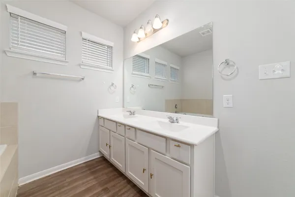 an empty room with wooden floor windows and fan