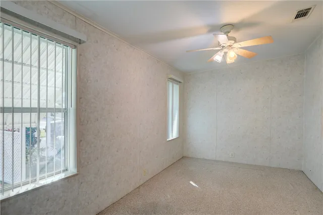 an empty room with windows and fan