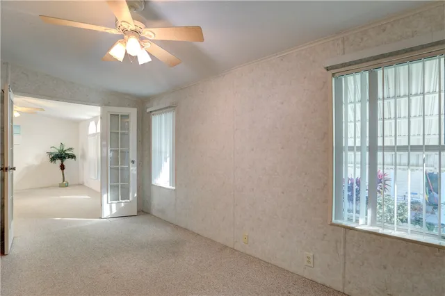 a view of a big room with windows and chandelier fan