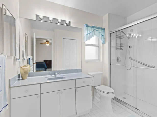 a bathroom with a granite countertop shower sink vanity mirror and toilet