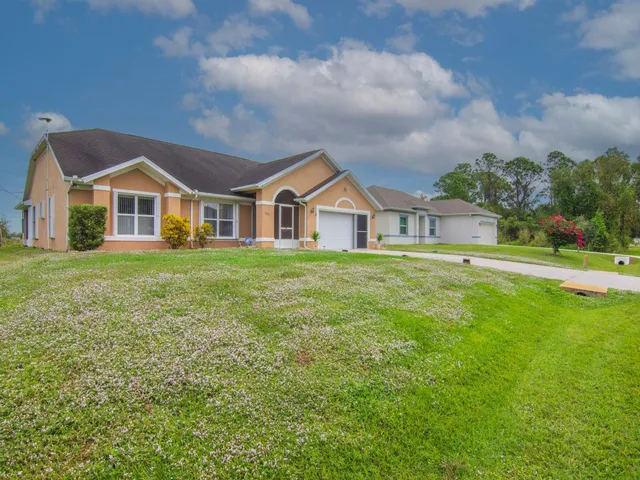 a view of a house with a big yard and large trees