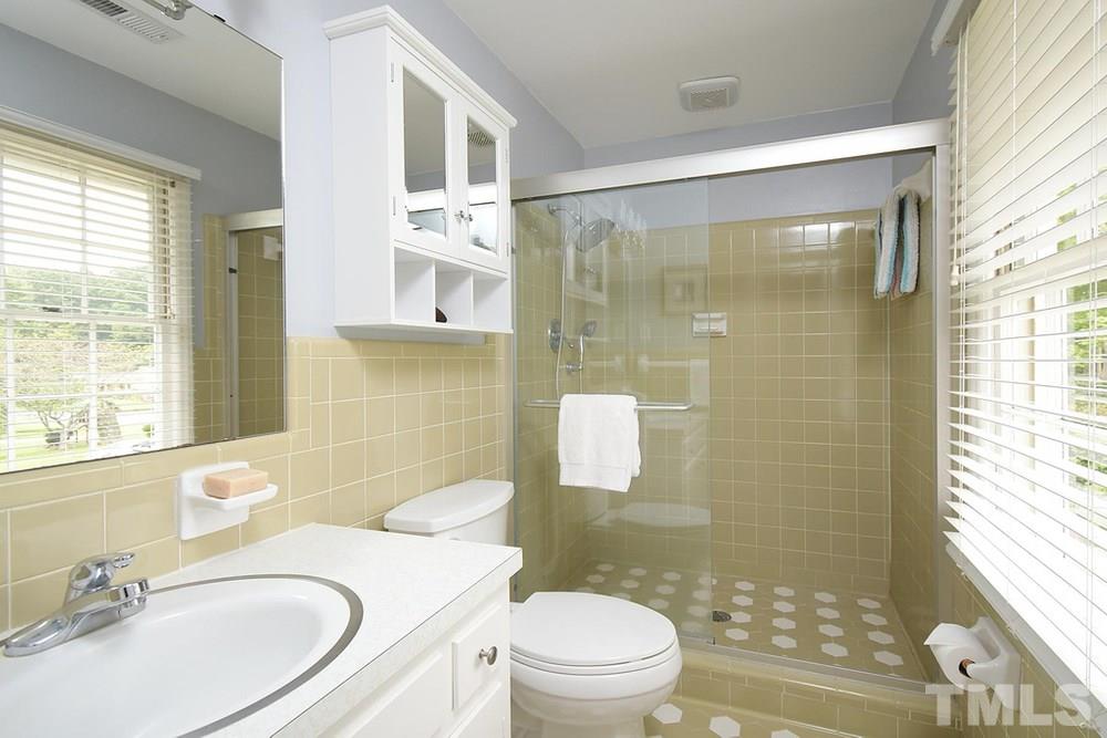 6405 Wrenwood Avenue Raleigh, NC 27607 - Photo 15 of 30 a bathroom with a sink a toilet a mirror and a shower