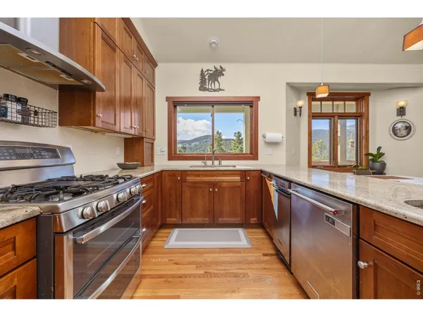 a kitchen with stainless steel appliances granite countertop a stove a sink dishwasher and cabinets with wooden floor