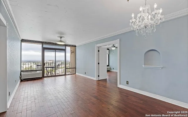 a view of an empty room with a window and wooden floor