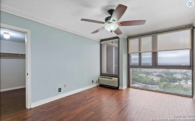 a view of room with window ceiling fan and wooden floor