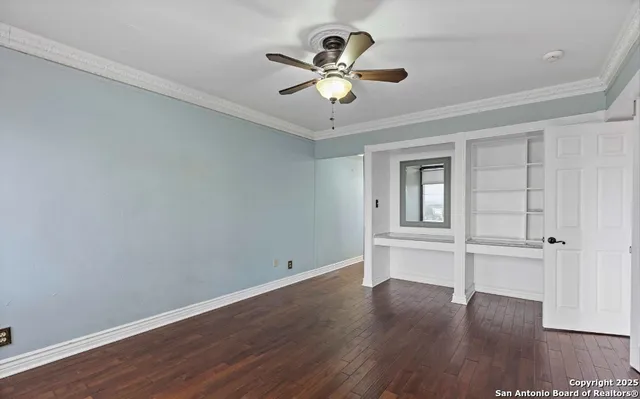 an empty room with wooden floor chandelier fan and windows