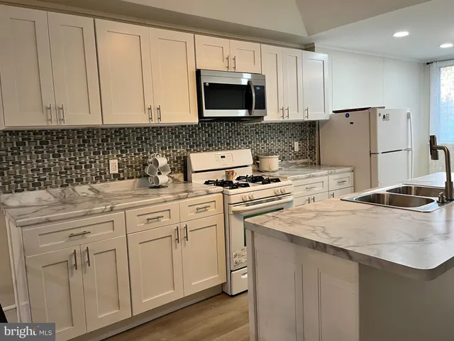 a kitchen with granite countertop white cabinets and stainless steel appliances