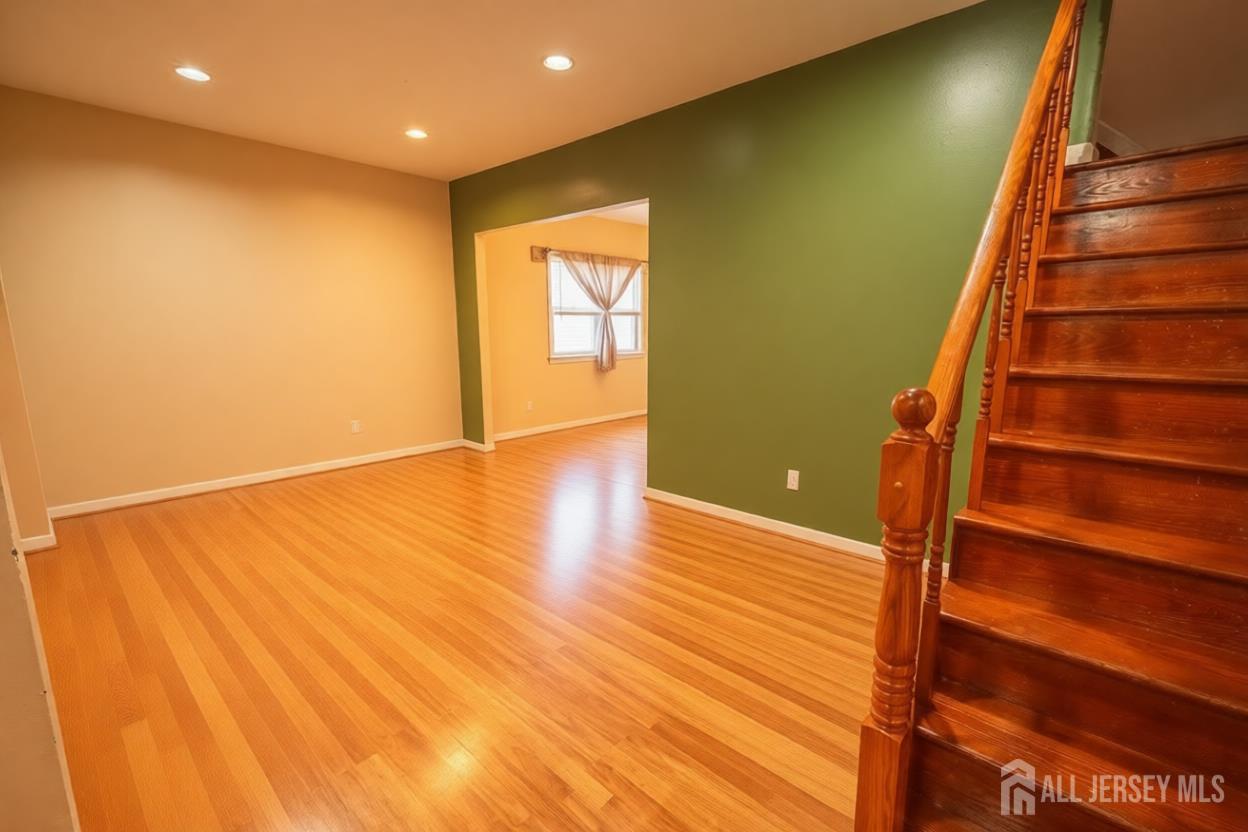 269 Silzer Street Perth Amboy, NJ 08861 - Photo 13 of 13 a view of an empty room with wooden floor and stairs