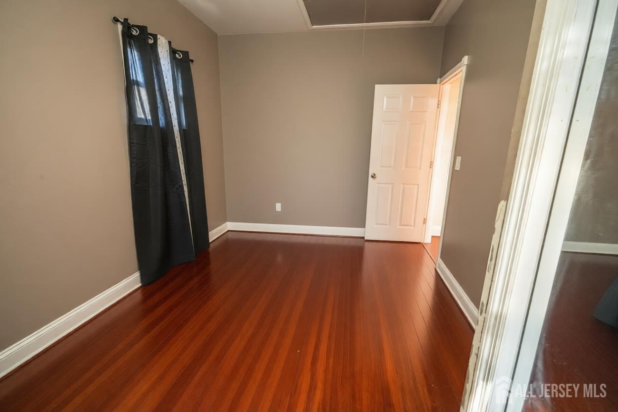 269 Silzer Street Perth Amboy, NJ 08861 - Photo 8 of 13 a view of an empty room with wooden floor and a window