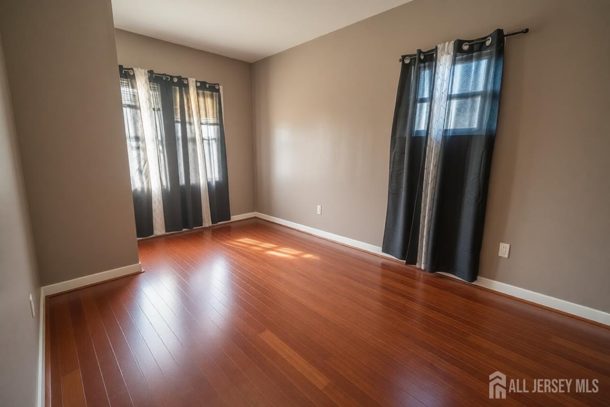 269 Silzer Street Perth Amboy, NJ 08861 - Photo 9 of 13 an empty room with wooden floor and windows
