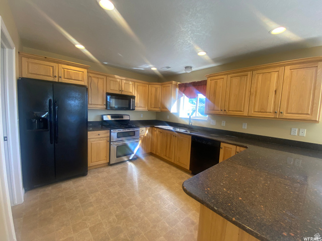 83 Canterbury Circle Logan, UT 84321 - Photo 4 of 23 Kitchen with black appliances, dark stone countertops, light floors, and recessed lighting