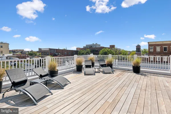 a view of a roof deck with table and chairs with wooden floor and fence