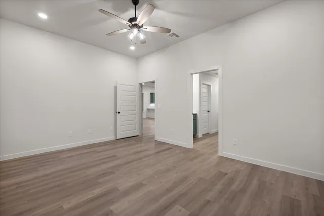 an empty room with wooden floor and ceiling fan