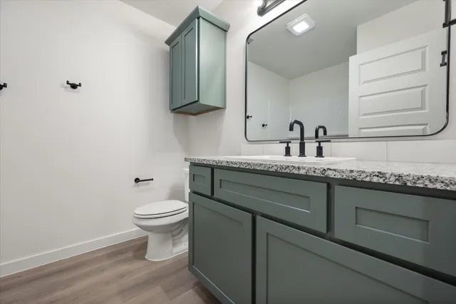 a bathroom with a granite countertop toilet sink and mirror