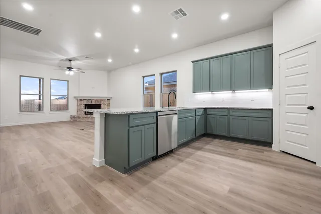 a large kitchen with stainless steel appliances granite countertop a large counter top a sink and a refrigerator