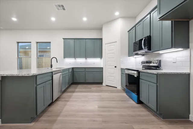 a kitchen with stainless steel appliances granite countertop a sink counter space cabinets and a large window