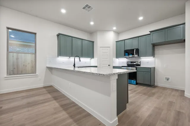 a large kitchen with kitchen island a sink stainless steel appliances and cabinets