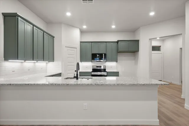 a large white kitchen with kitchen island granite countertop a sink and a refrigerator