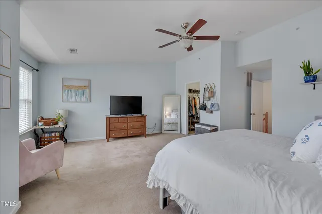 a spacious bedroom with a bed and a flat screen television