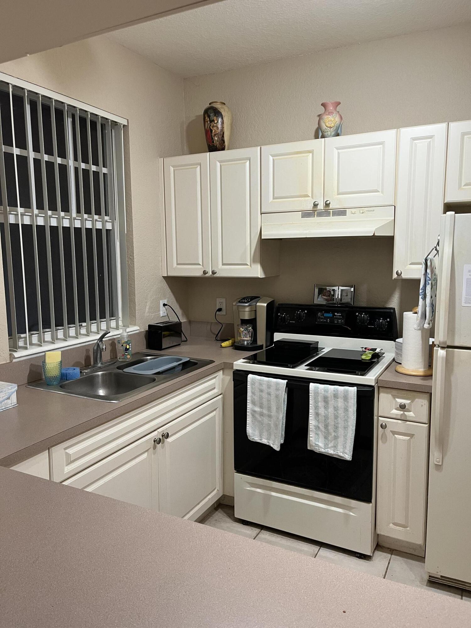 6890 West Sample Road, Unit 6890 Pompano Beach, FL 33063 - Photo 5 of 10 a kitchen with stainless steel appliances a stove a sink and a microwave