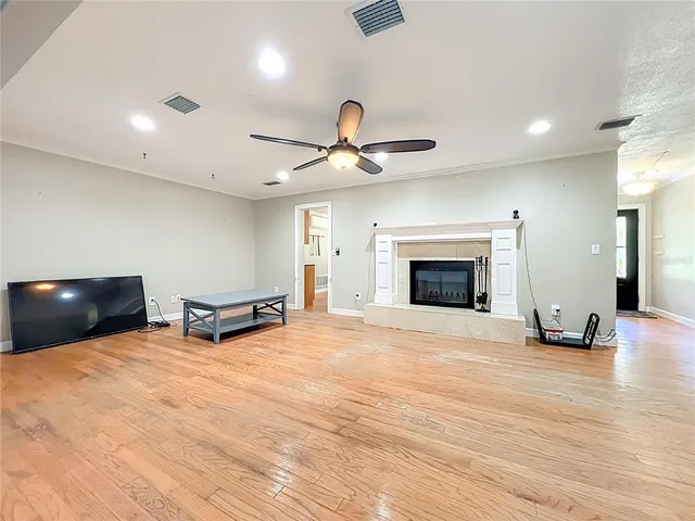 an empty room with wooden floor chandelier fan and windows