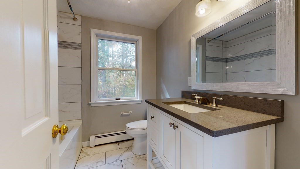 7 Nehemiah Road Shirley, MA 01464 - Photo 29 of 37 a bathroom with a granite countertop sink and a mirror with bathtub