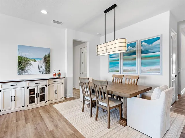 a kitchen with stainless steel appliances a stove a sink a center island a refrigerator and a wooden floor