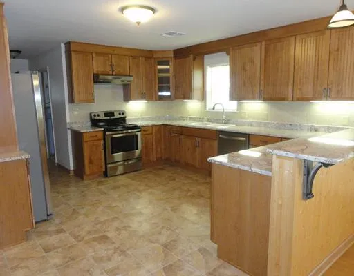 a kitchen with stainless steel appliances granite countertop a refrigerator a stove a sink and dishwasher