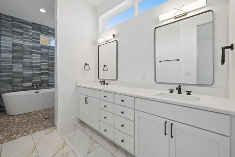 a bathroom with a double vanity sink mirror and bathtub