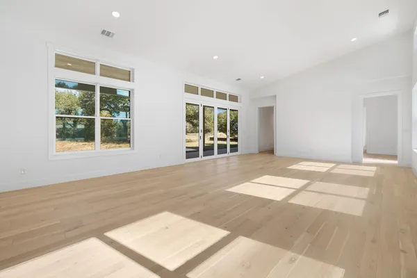 a view of an empty room with wooden floor and windows