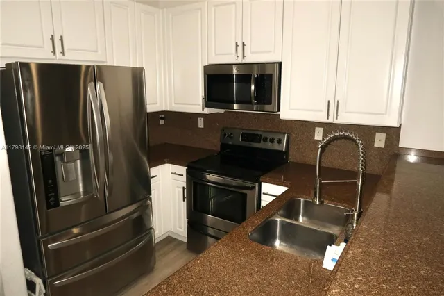 a kitchen with stainless steel appliances granite countertop a refrigerator and a stove top oven