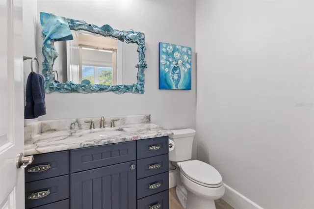 a bathroom with a granite countertop toilet sink and mirror