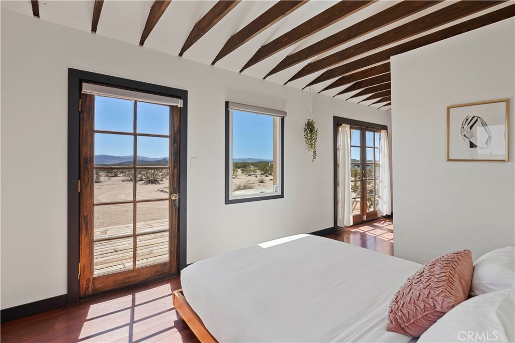 66750 Pole Line Road Joshua Tree, CA 92252 - Photo 17 of 36 a bedroom with a bed and wooden floor