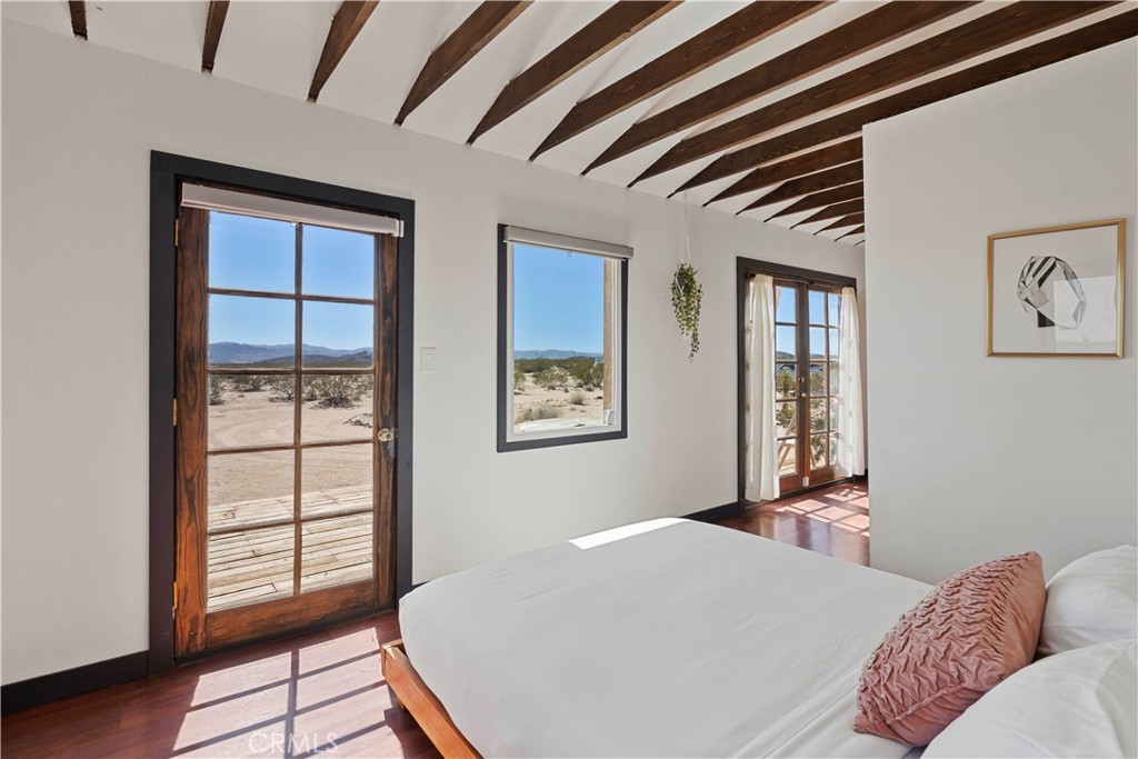 66750 Pole Line Road Joshua Tree, CA 92252 - Photo 17 of 36 a bedroom with a bed and wooden floor