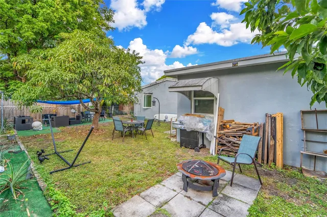 a view of a patio with table and chairs potted plants and a large tree