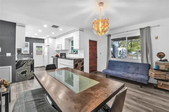 a kitchen with stainless steel appliances granite countertop a stove refrigerator and couches with wooden floor