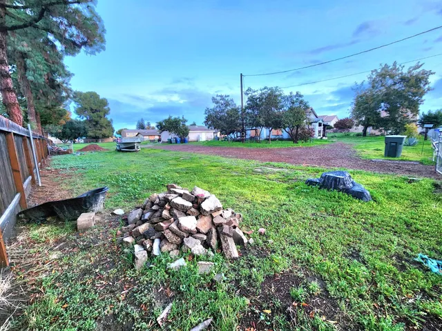 a view of a garden with a bench in front of the house