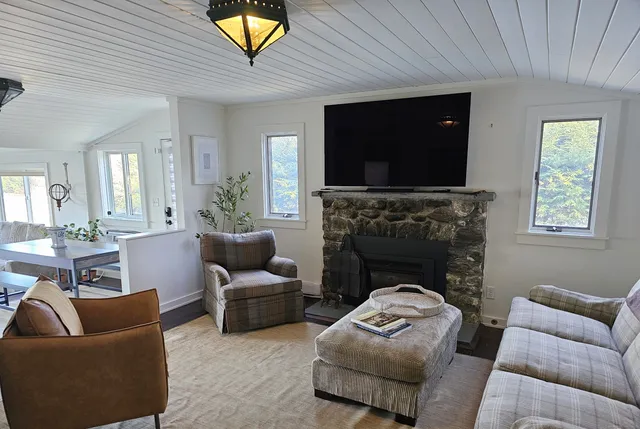 a living room with furniture large windows and wooden floor
