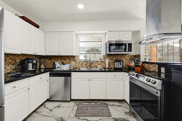 a kitchen with granite countertop a stove a sink and a microwave